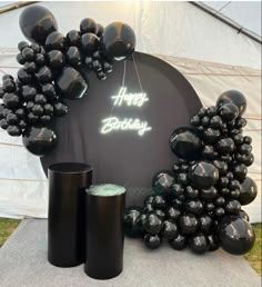 black balloons and candles are on display in front of a sign that says happy birthday