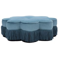 a blue ottoman with fringes on the top and bottom, in front of a white background