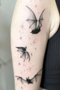 a woman's arm with two bats on it and stars in the sky above