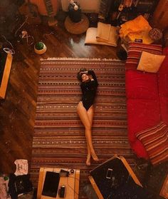 a woman laying on top of a wooden floor next to a red couch