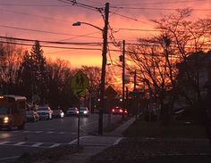 the sun is setting over a city street with cars and buses driving down the road