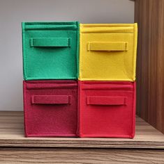 four different colored storage bins sitting on top of a wooden table next to a wall