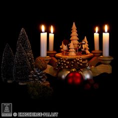 christmas decorations with lit candles and baubles in front of them on a black background