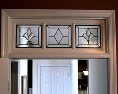 three stained glass windows above the door to a home's entryway and kitchen