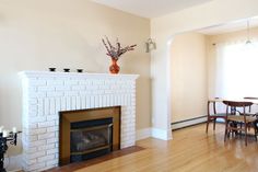 a living room filled with furniture and a fire place next to a dining table on top of a hard wood floor