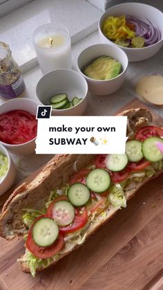 a sub sandwich with cucumbers, tomatoes, onions and lettuce on it