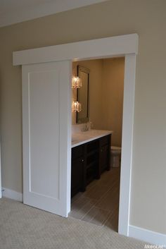 an open door leading to a bathroom with a sink and mirror on the opposite wall