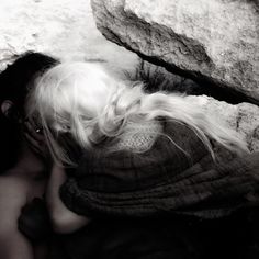 two people are kissing in front of some large rocks and one is wearing a hat