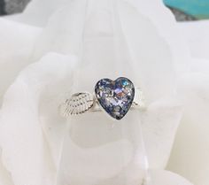 This stunning sterling silver heart and double angel wing band ring is made with cremation ashes. The cremation "stone" heart is 8mm and the band is 3mm wide. *All the pieces in my cremation collection have a finished look that resemble glass or stone once set. I do make these pieces with the ashes visible, however you can specify in a note to me if you would prefer not to see the ashes. I take great care in creating these special keepsakes and I can assure you that all cremains/ashes will be handled with dignity.***Process***Ashes are delicately and precisely set by hand in a clear jeweler's resin blend solution along with your chosen inclusion materials (glitter, shimmer flakes, colorant, crushed glass, etc.). This process solidifies your ashes and creates a memorial "stone".*I have many Urn Ring, Wings Band, Pet Ashes Jewelry, Loss Of Pet, Cremation Ring, Angel Wings Heart, Pet Keepsake, Memorial Ring, Pet Cremation