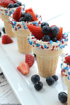 three ice cream cones with strawberries, blueberries and strawberries in them on a white plate