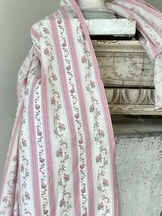 a pink and white striped blanket sitting on top of a table next to an old chest