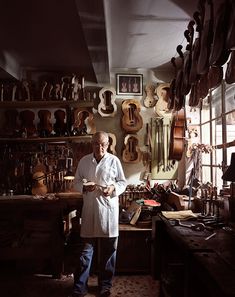 a man standing in a room filled with lots of musical instruments on the wall and shelves