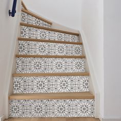 the stairs are decorated with black and white tile designs, along with wooden handrails