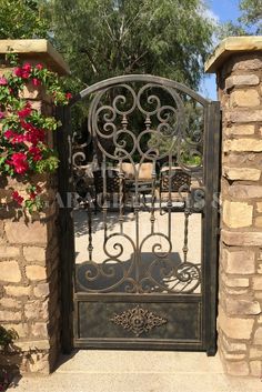 an iron gate with flowers growing on the side and brick pillars in front of it