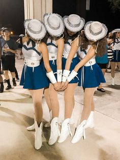 the girls are dressed in blue and white outfits with hats on their heads, while one girl is holding her hands behind her back