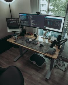 two computer monitors sitting on top of a wooden desk