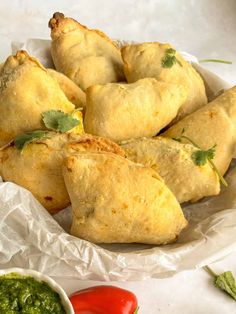 some tasty looking pastries are on a white plate with sauces and herbs