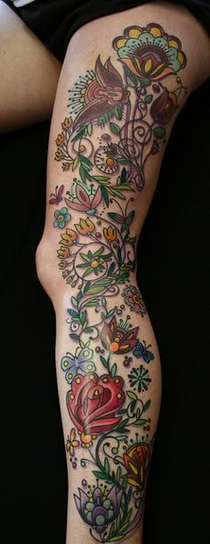 a woman's legs with tattoos on them and flowers all over the leg area