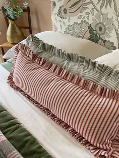 the pillows are stacked on top of each other in front of a floral headboard