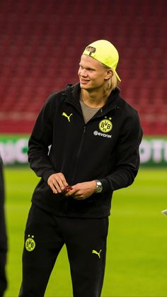 a man with a yellow hat standing on a soccer field