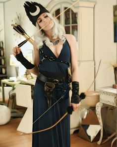 a woman dressed up as a witch with two arrows in her hand and wearing a costume