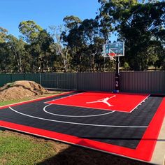 an outdoor basketball court is painted red and black