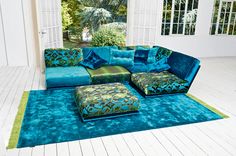 a large blue couch sitting on top of a wooden floor next to a green rug