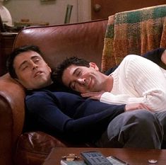 two men laying on a couch next to each other