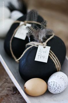 some eggs are sitting on top of black and white rocks with tags attached to them