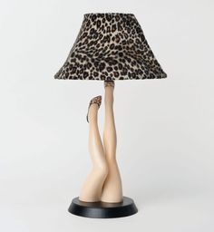 a lamp that has a leopard print shade on it and two legs in front of the lamp