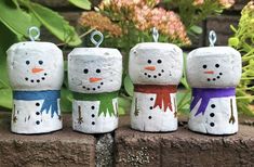 four snowmen are sitting on top of a brick wall in front of some flowers