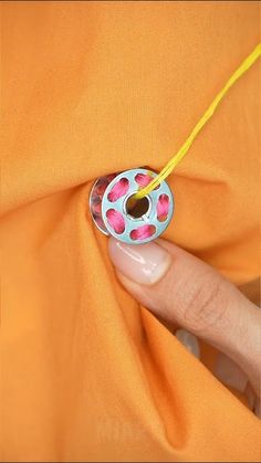 a woman's hand holding onto an orange fabric with pink and white circles on it