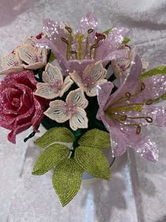 a vase filled with pink and green flowers on top of a white cloth covered table