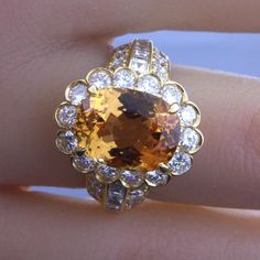 an orange and white diamond ring sitting on top of someone's finger in front of the camera