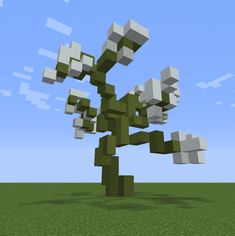 a tree made out of cubes in the middle of a grassy area with blue sky and clouds