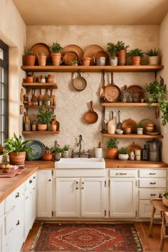 a kitchen filled with lots of pots and pans on shelves above a sink under a window