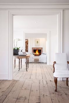 a living room filled with white furniture and a fire place in the middle of it