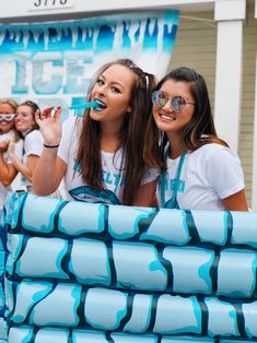 two girls in white shirts are brushing their teeth with toothpaste on blue tubes