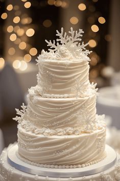 a wedding cake with white frosting and snowflakes on the top is sitting on a table