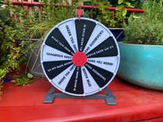 a black and white spinning wheel sitting on top of a red table next to potted plants