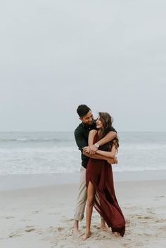 an engaged couple hugging on the beach