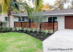 a house with palm trees in front of it and a fence around the yard area