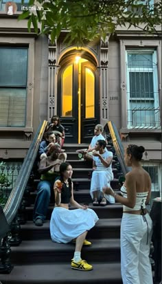 several people sitting on the steps of a building with one woman in a white dress