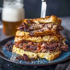 a stack of french toast on a blue plate next to a glass of beer with a knife stuck in it