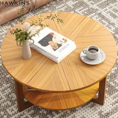 a coffee table with a book, cup and vase on it next to a rug