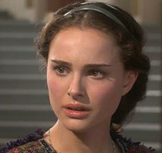 the woman is standing in front of stairs wearing a necklace and looking at the camera