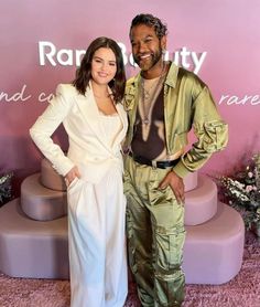 a man and woman standing next to each other in front of a pink carpeted wall