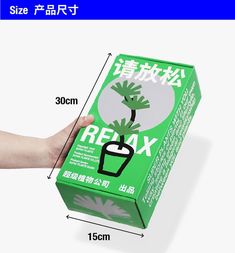 a person holding up a green box with an image of a plant on it and the words relax written in chinese