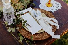 a place setting with napkins, silverware and flowers on a wooden table outdoors