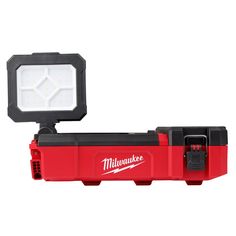 the milwaukee light is on top of a red toolbox with its lights on it